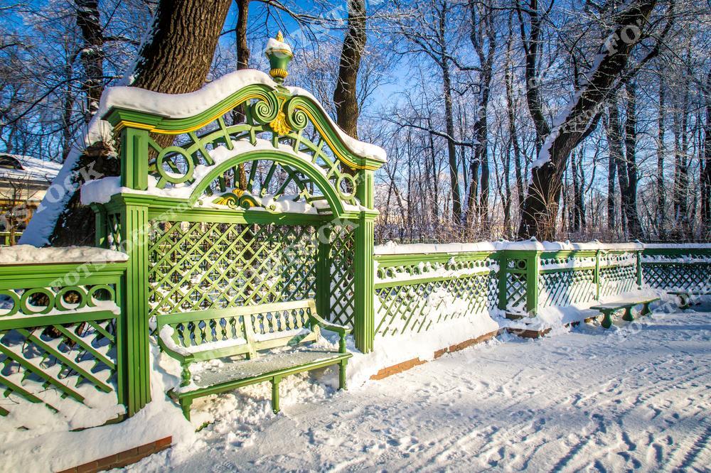 Фотография запечатлела заснеженную скамейку в Летнем саду Санкт-Петербурга. Скамейка оформлена зелеными деревянными решетками и резными элементами, что придает ей классический вид. Летний сад — одно из любимых мест для прогулок горожан и туристов в любое время года!